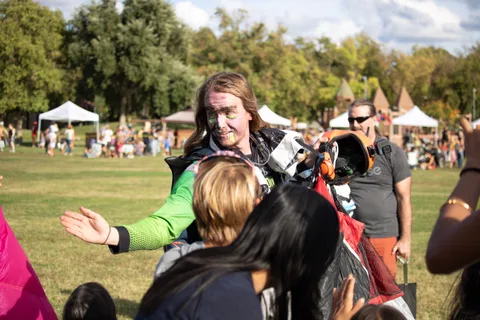 A skydiver in face paint reaches out to a child in the crowd.