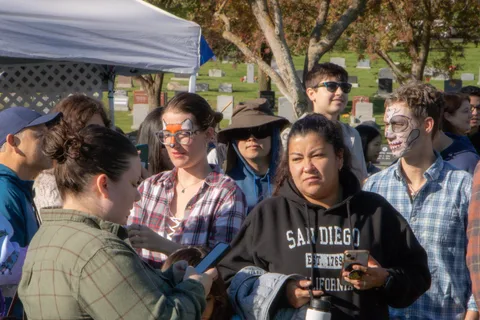 People gather at a festival booth under a canopy
