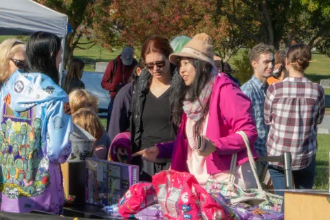 Visitors look over bright goods laid out on a vendor table