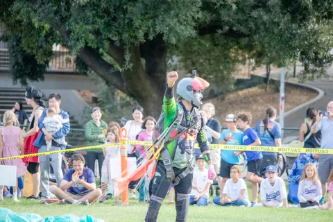 A skydiver gathers up gear at the edge of the crowd.