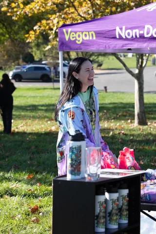A smiling volunteer at a booth with festival merchandise