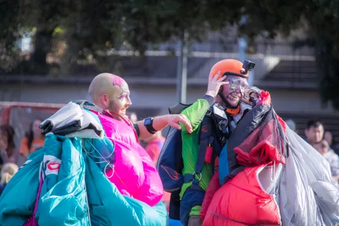 Two skydivers in face paint stand with their canopies gathered.