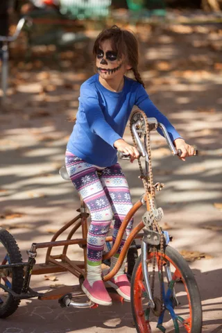 A girl in patterned leggings rides a chopper-style bike.
