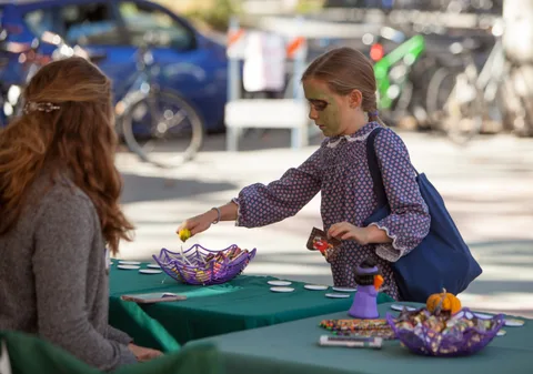 A girl reaches for a craft item at a decorated activity table.