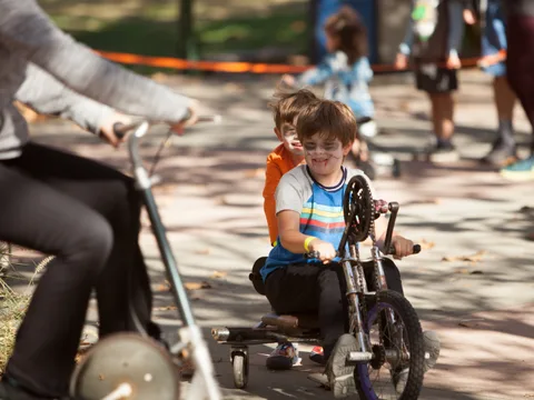 Kids ride small trick bikes down a path.