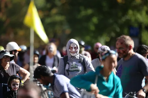 Costumed pedestrians walk together down a sidewalk.