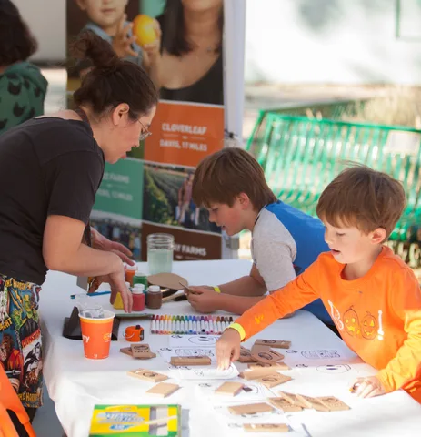 Two boys decorate wooden stamps at a craft table sponsored by Cloverleaf Farms.