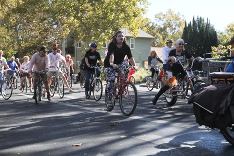 Riders move together on a sunlit downtown street.