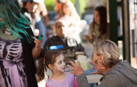 A group with a teal-haired woman and children gathers casually.