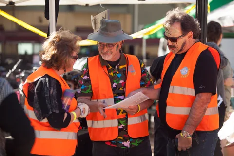 Volunteers in orange safety vests confer near the event area.