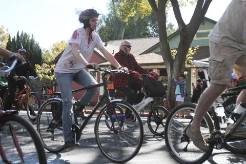 A rider with blood-stained white clothing pedals through the crowd.