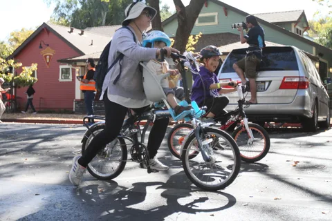 A family with kids on bikes gathers near a parked van.