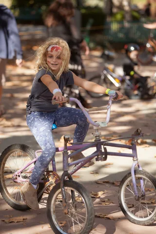 A rider in patterned leggings pedals a low chopper-style trike.