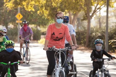 Two riders in a pumpkin shirt and baseball cap ride toward the camera.