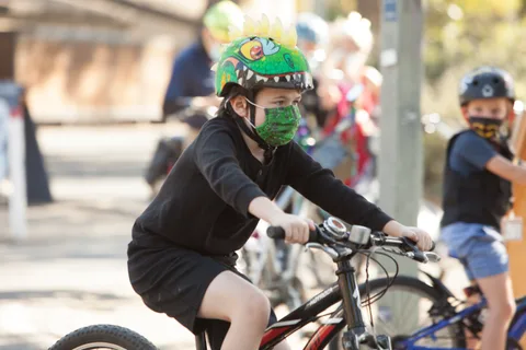A rider in a green helmet pedals away with other cyclists in the background.