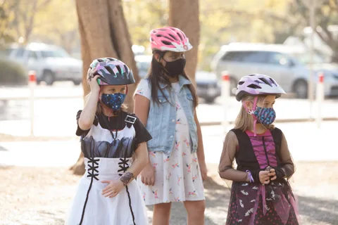 Two girls in costumes and masks stand together, one in a white dress.