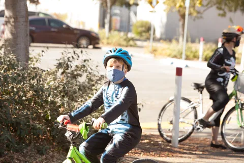 A child in a blue helmet sits in front while an adult in dark costume stands behind.