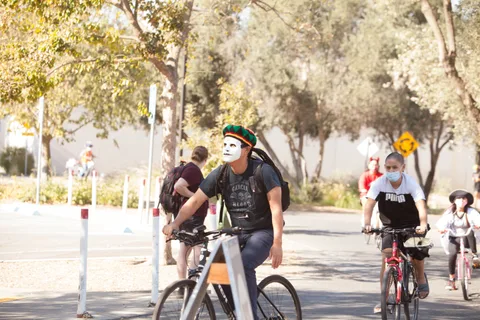 A man in a white skull mask rides with others behind him.