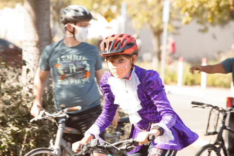 A rider in a sequined purple jacket rides beside another cyclist.