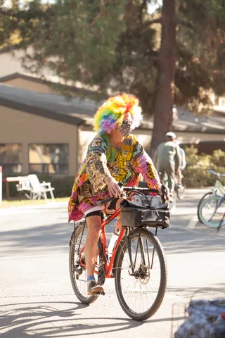 A rider in a patchwork costume pedals away down the path.