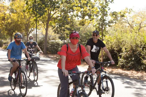 Three riders stand together with their bikes on the path.