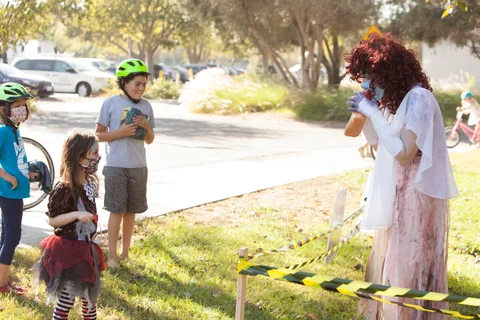A family stands at a caution-tape barrier with a costumed figure in the distance.
