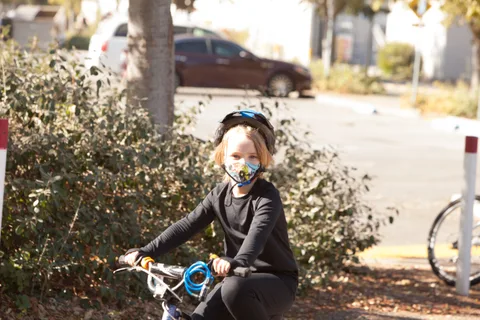 A rider in a teal helmet passes through dappled shade on the path.