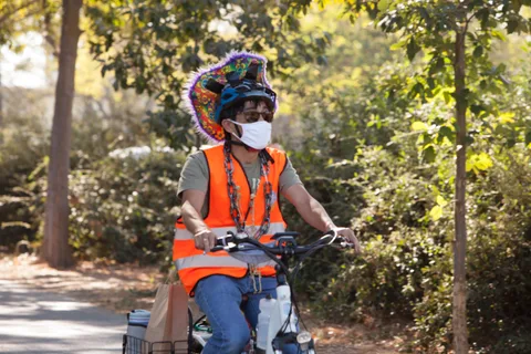 A masked rider in a patterned headscarf and orange safety vest rides the route.