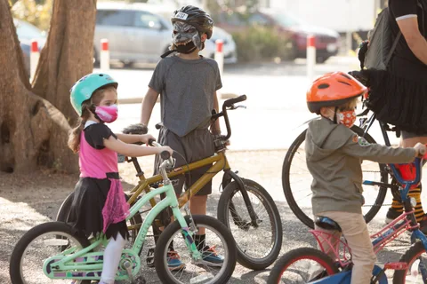 Kids stand with their bikes at a rack.