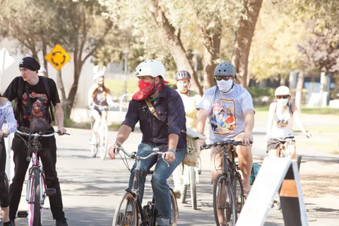 Three masked riders including one in a white helmet ride together.