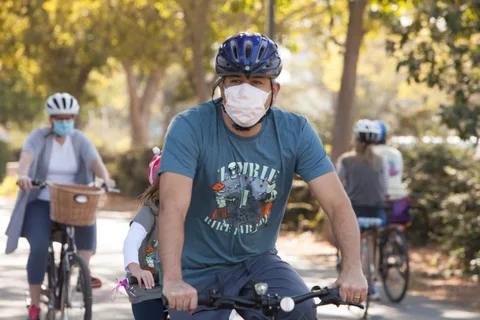 A masked rider pauses on the path with others nearby.