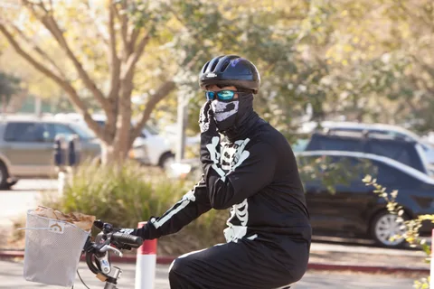 A rider in a full skeleton bodysuit leans into a turn mid-pedal.
