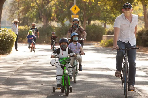 A line of riders including kids approaches the camera past a road sign.