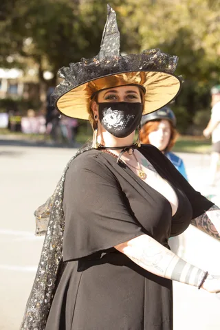 Two women in pirate and witch costumes stand close together, fabric partly covering their faces.