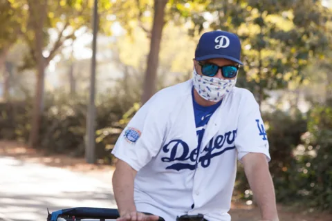 A man in a white baseball jersey and cap rides alone.
