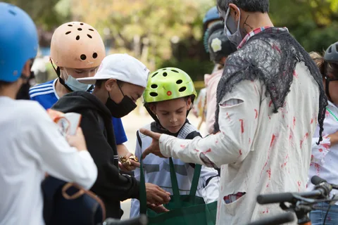 A group of kids in helmets gathers on the sidewalk.