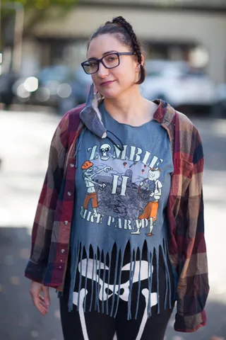 A woman in glasses and a zombie-print shirt looks calmly at the camera.