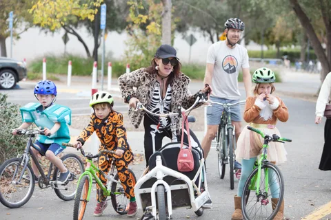 A family in skeleton costumes gathers with their bikes for a group photo.