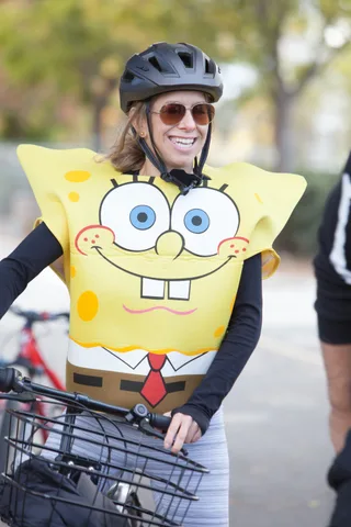A woman in a full SpongeBob SquarePants costume laughs in the sun.