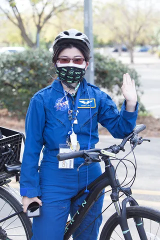 A close crop shows a blue jumpsuit costume with an ID badge, face out of frame.