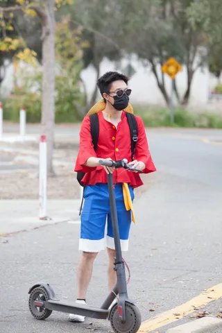 A masked rider on a scooter pauses on an empty street.