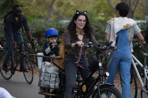 A family in costume walks their bikes along the path, one in a leopard-print hood.