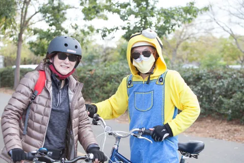 A rider in a yellow minion costume waits with a friend on the bike path.