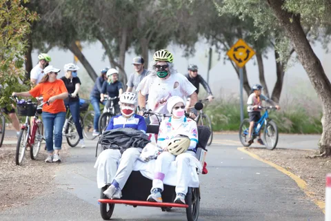 A line of riders in white skeleton costumes rides down the tree-lined path.