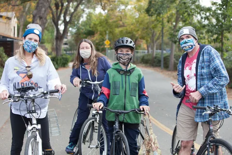 A small group of masked riders pauses together on the bike path.