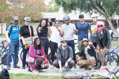 A large group of friends in mixed costumes poses together on the sidewalk.