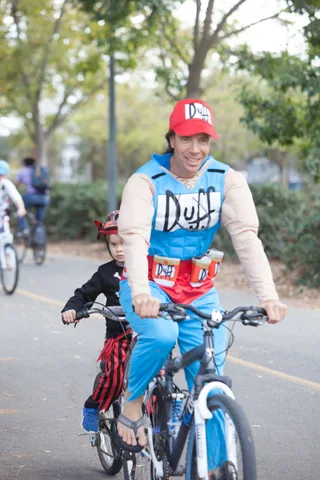 A rider in a red cap and cartoon beer-brand costume shirt smiles for the camera.