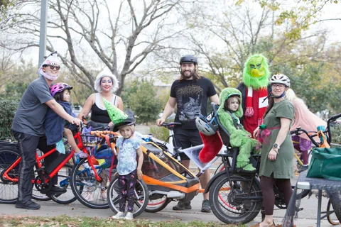 A cluster of costumed families with bikes gathers on the path.