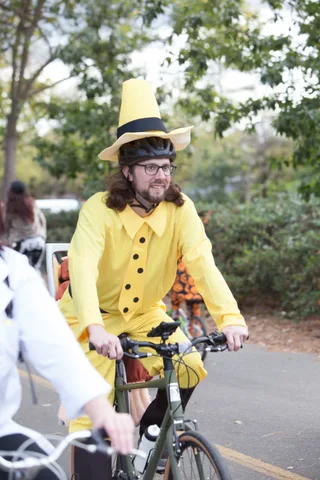 Two riders in yellow costumes are cropped at the torso while riding bikes.