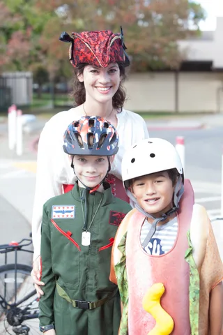 Two kids in white helmets and costumes smile together for the camera.